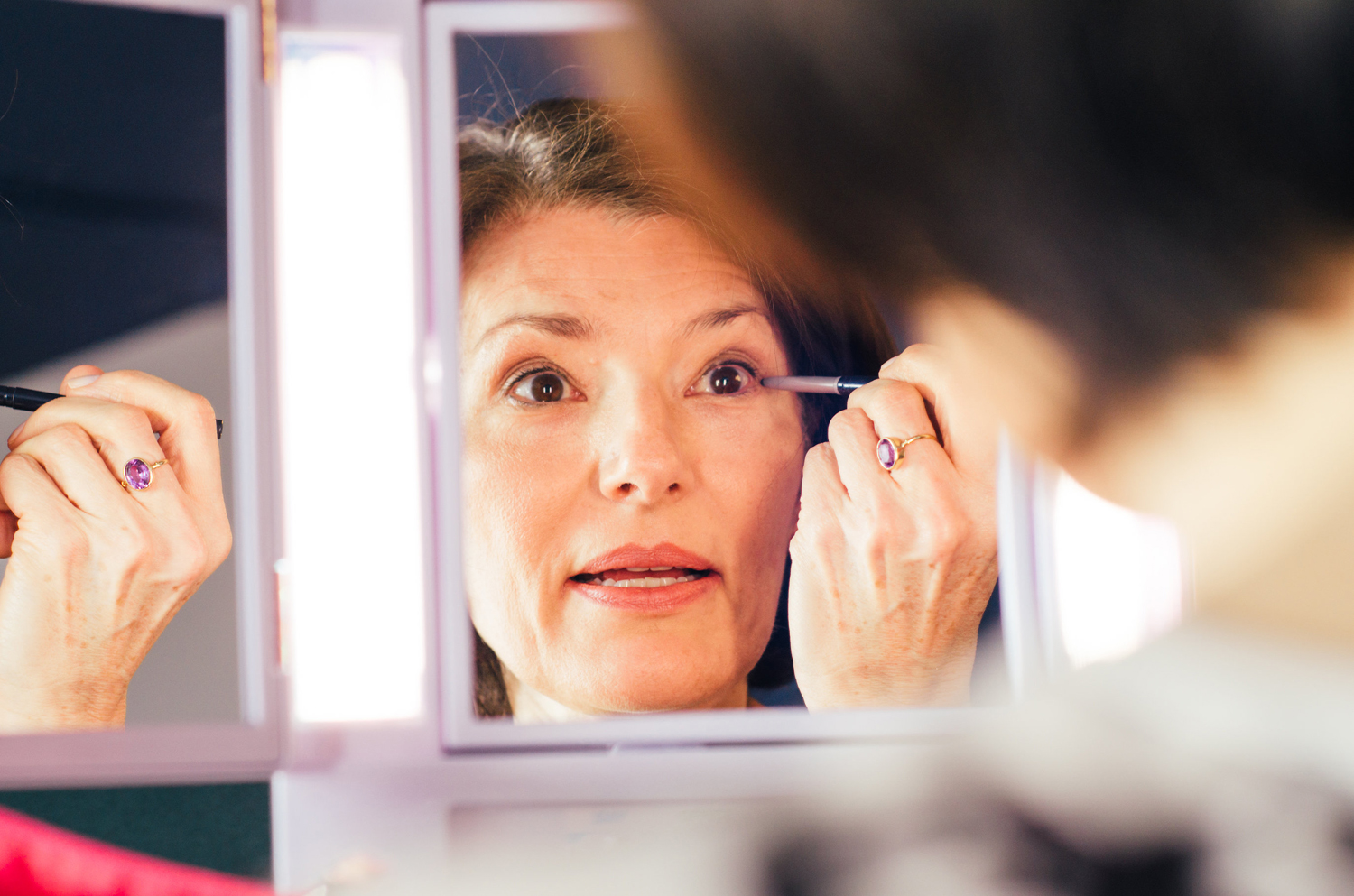 Femme se maquillant dans le miroir.